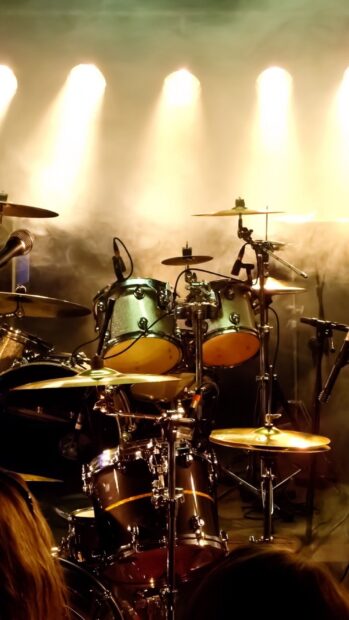 A drum set is prepared on stage with bright lights and microphones, HD Mobile Wallpaper