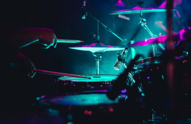 A close up of drums being played with purple and blue stage lights highlighting the scene, 2K Desktop Wallpaper