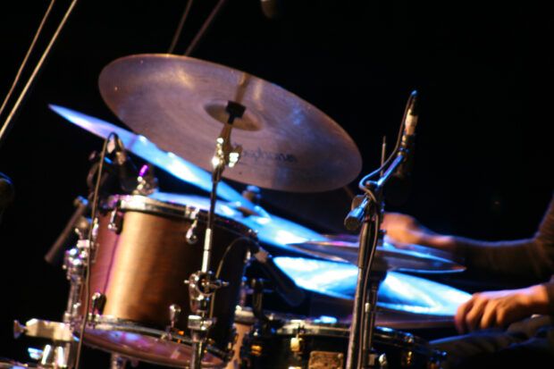 A drummer is playing drums with cymbals and microphones on stage, HD Desktop Wallpaper
