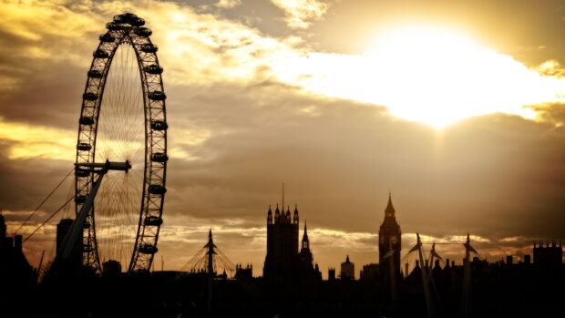 The London Eye stands tall against a dramatic sunset sky with the city skyline in the background, 4K Desktop Wallpaper