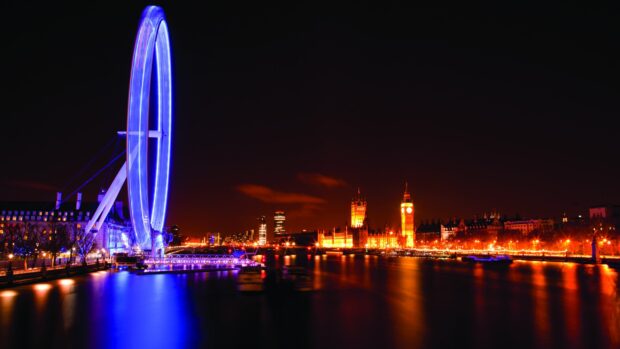 The London Eye glows bright blue at night over the River Thames against a city skyline, 2K Desktop Wallpaper