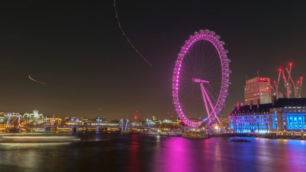 The London Eye stands brightly lit by the river Thames during nighttime, 4K Desktop Wallpaper