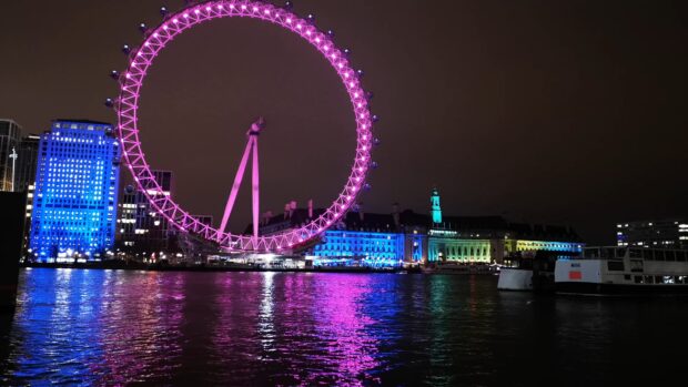 The London Eye is illuminated in pink with colorful lights reflecting on the river, 4K Desktop Wallpaper