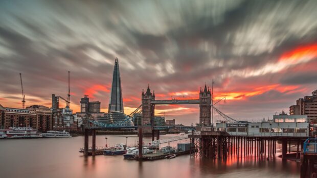 The London skyline at sunset shows the Tower Bridge and the Shard with dramatic clouds, 4K Desktop Wallpaper