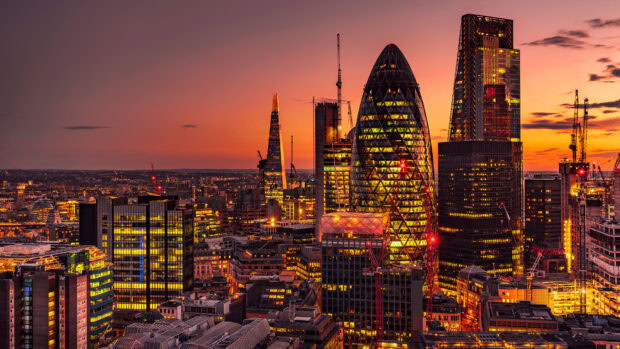 The London skyline glows warmly at sunset with iconic skyscrapers lit up, 4K Desktop Wallpaper