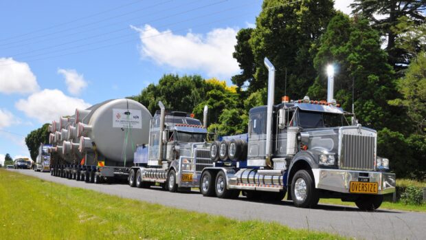 A Kenworth truck transporting an oversized industrial load on a rural road, 2K Desktop Wallpaper