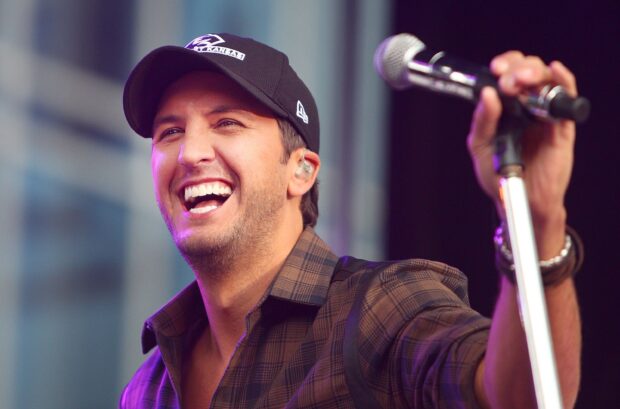 Luke Bryan is smiling and holding a microphone during a live performance, 2K Desktop Wallpaper
