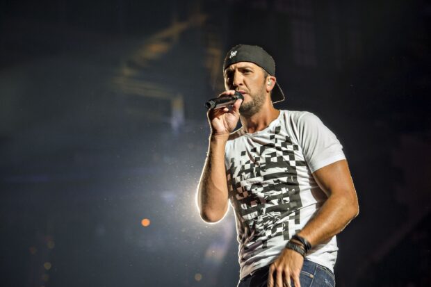 Luke Bryan is singing on stage during a concert with dynamic lighting, 2K Desktop Wallpaper