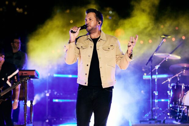 Luke Bryan is singing passionately during a live concert with colorful stage lights, 2K Desktop Wallpaper