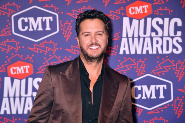 Luke Bryan is smiling at the CMT Music Awards event with a patterned background, 2K Desktop Wallpaper
