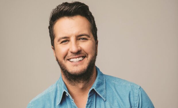 Luke Bryan smiles warmly in a casual blue shirt against a neutral background, 2K Desktop Wallpaper
