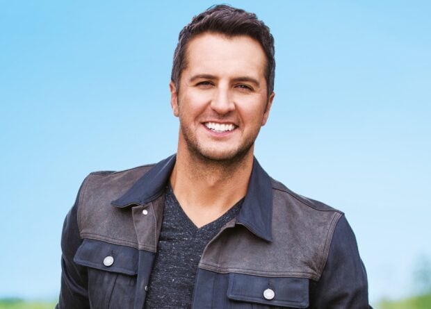 Luke Bryan smiles warmly in a casual jacket against a clear blue sky, HD Desktop Wallpaper
