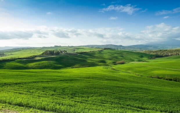 A scenic view of green hills stretching under a partly cloudy sky, HD Desktop Wallpaper