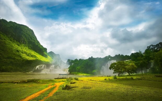 The green hills create a peaceful landscape with waterfalls in the background, 2K Desktop Wallpaper