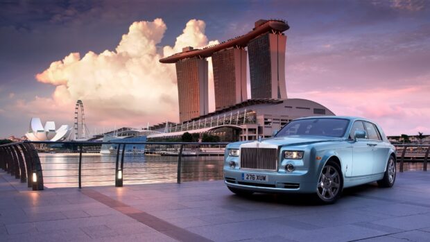 A Rolls Royce Phantom is parked by the scenic waterfront with iconic city architecture in the background, HD Desktop Wallpaper
