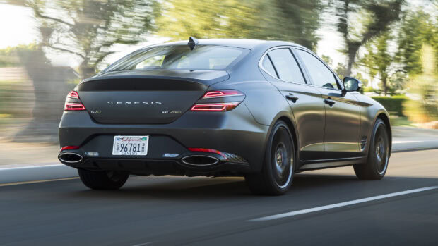A luxury Genesis car is shown driving on a city street with blurred trees in the background, 2K Desktop Wallpaper