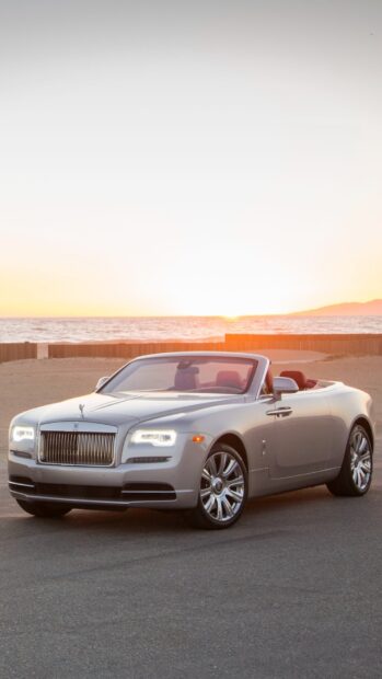 A silver Rolls Royce Dawn convertible parked by the ocean during sunset with a clear sky, HD Phone Wallpaper