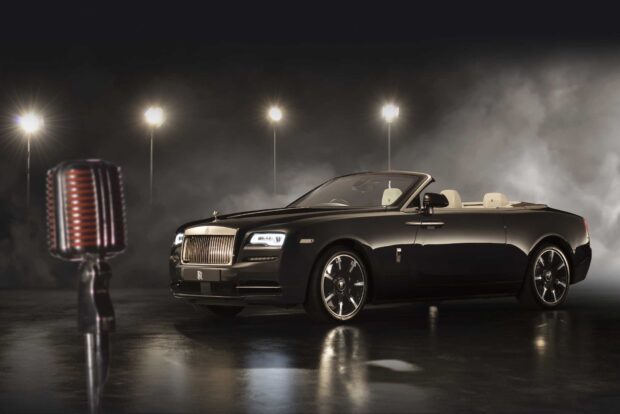 A Rolls Royce Dawn is parked indoors with dramatic lighting and a vintage microphone nearby, HD Desktop Wallpaper