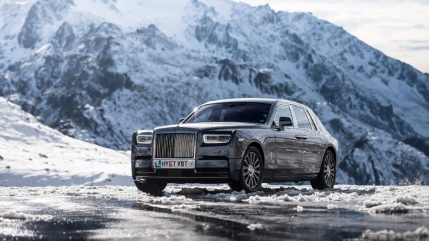 A sleek Rolls Royce Phantom standing on snowy ground with rugged mountains behind, 4K Desktop Wallpaper
