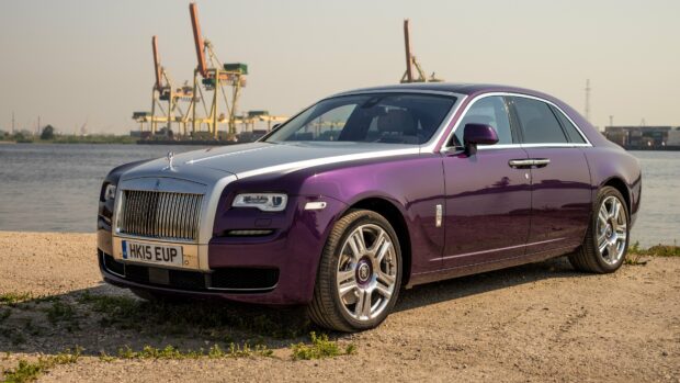 A purple and silver Rolls Royce Ghost is parked by the water with cranes in the background, 4K Desktop Wallpaper