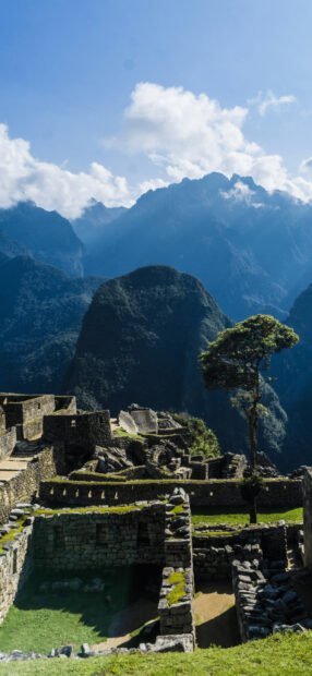 Ancient Machu Picchu ruins surrounded by mountains under a blue sky