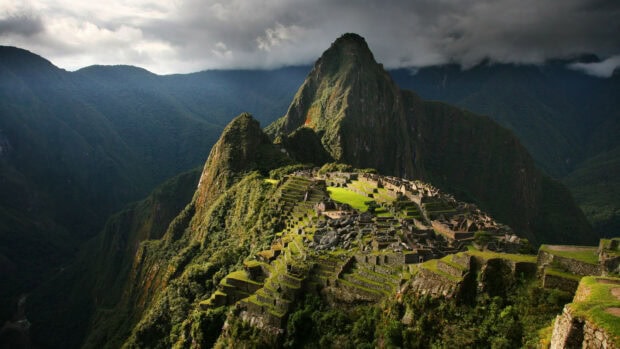 Machu Picchu ancient site surrounded by lush mountains and cloudy sky