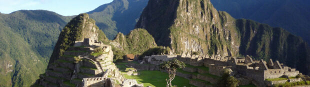 Ancient Machu Picchu ruins surrounded by lush green mountains under clear blue sky