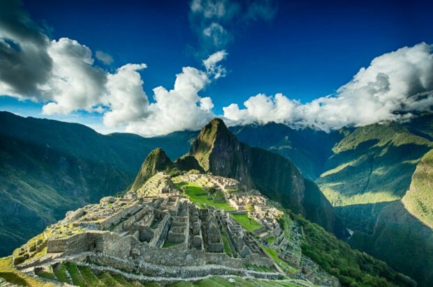 Ancient Machu Picchu ruins surrounded by lush mountains under a bright blue sky