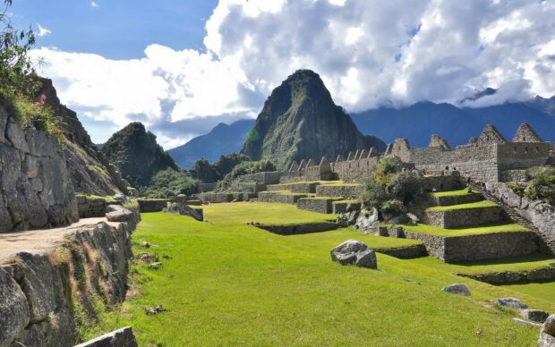 Ancient Machu Picchu ruins with mountain landscape and green grass under a blue sky