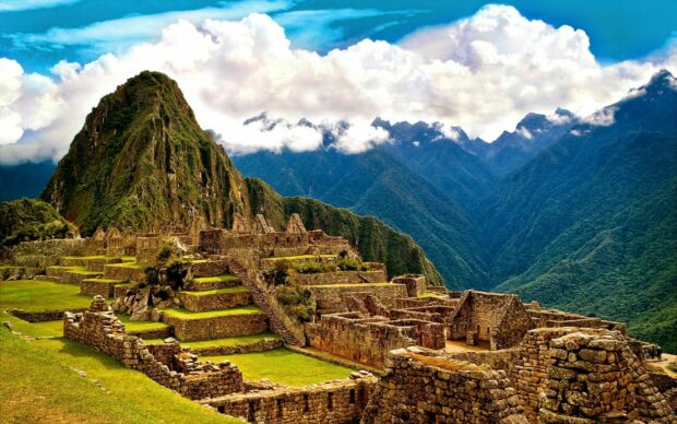 Ancient Inca ruins at Machu Picchu surrounded by lush green mountains and cloudy sky