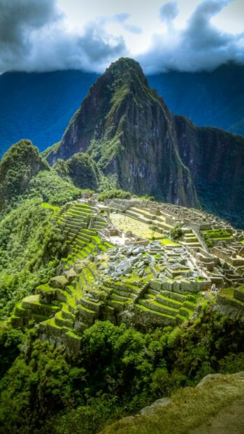 Ancient Machu Picchu ruins surrounded by lush green mountains under cloudy sky