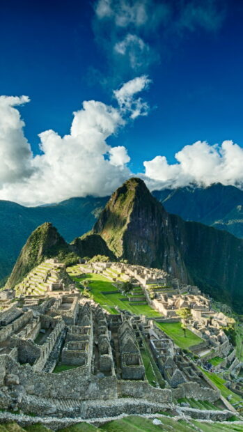 Ancient Machu Picchu ruins surrounded by lush mountains and vibrant clouds