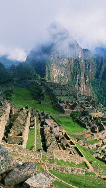 Ancient Machu Picchu ruins surrounded by green mountains and mist