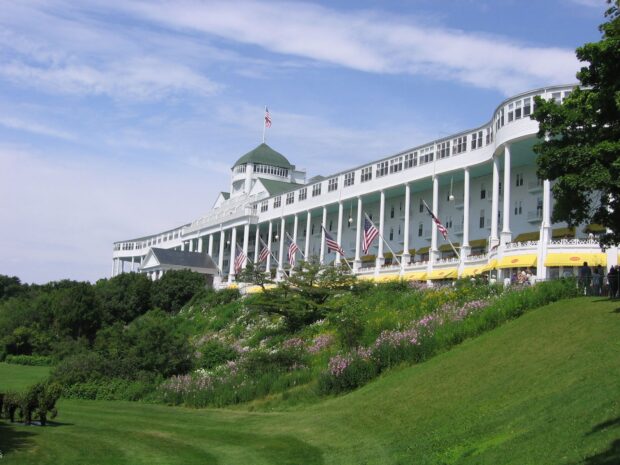 The Mackinac Island grand hotel stands on a green hill with flowers under a blue sky, HD Desktop Wallpaper