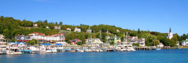 A scenic harbor view of Mackinac Island with boats and hillside houses, 2K Desktop Wallpaper