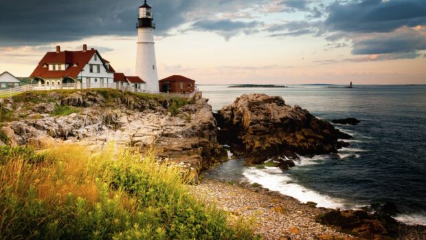 A lighthouse stands on rocky shores with the ocean and sky in Maine wallpapers, 2K Desktop Wallpaper