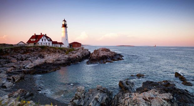 A lighthouse stands on the rocky coastline capturing the essence of Maine wallpapers, 2K Desktop Wallpaper