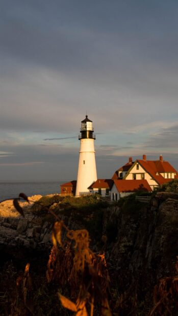 The Maine lighthouse stands tall with nearby houses under a colorful sky, HD Mobile Wallpaper
