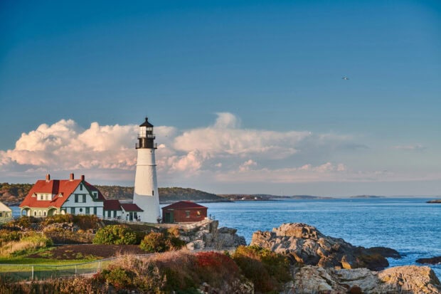 A white lighthouse stands on the rocky Maine coast with blue skies and ocean, HD Desktop Wallpaper