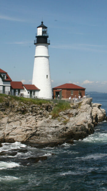 The Maine lighthouse stands tall on rocky cliffs by the ocean under a clear sky, HD Mobile Wallpaper