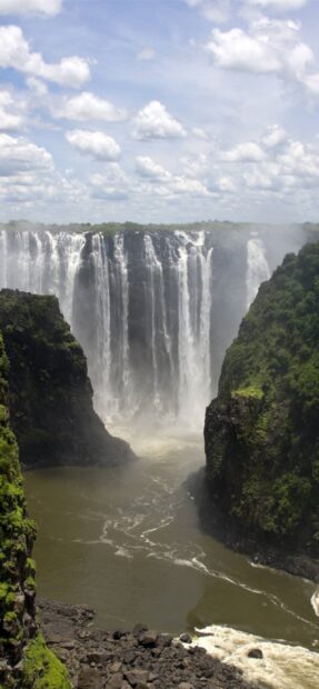 A breathtaking Ethiopia waterfall cascades between lush green cliffs under a cloudy sky, 2K Mobile Wallpaper
