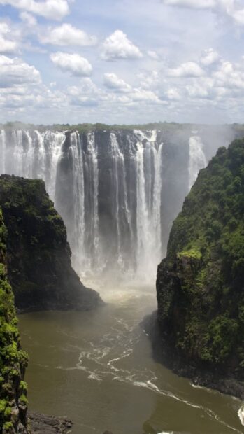 A majestic waterfall flows between green cliffs under a cloudy sky in Ethiopia, HD Mobile Wallpaper