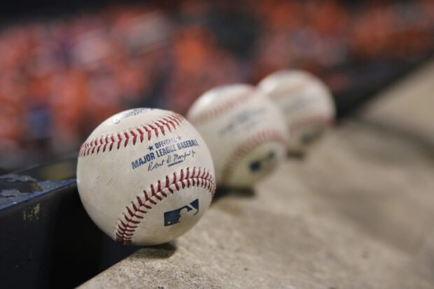 A close up of an official Major League Baseball with three baseballs blurred in the background, 2K Desktop Wallpaper