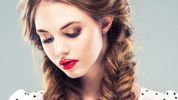 Young woman with makeup looking down with elegant lipstick and eyeshadow