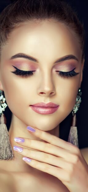Close up of makeup on a young woman with colorful eyeshadow and purple nails