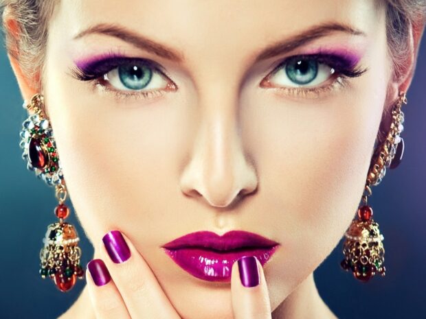 Close up of makeup on the woman with purple lipstick and matching nail polish