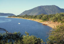 A scenic view of Malawi lake shore with boats and lush hills in the background, HD Desktop Wallpaper