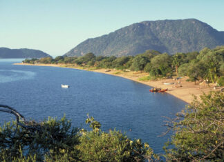A scenic view of Malawi lake shore with boats and lush hills in the background, HD Desktop Wallpaper