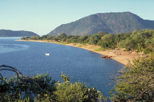 A scenic view of Malawi lake shore with boats and lush hills in the background, HD Desktop Wallpaper