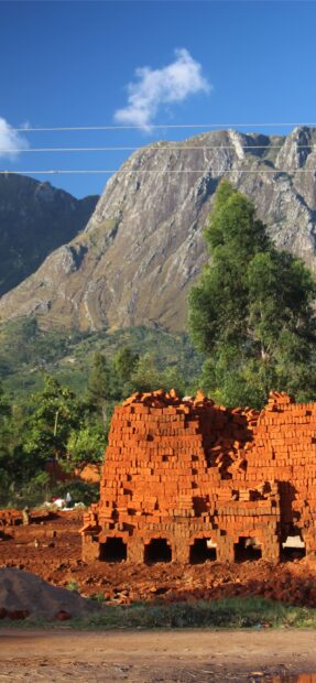 Red clay bricks stacked with trees and mountains in Malawi, 2K Mobile Wallpaper